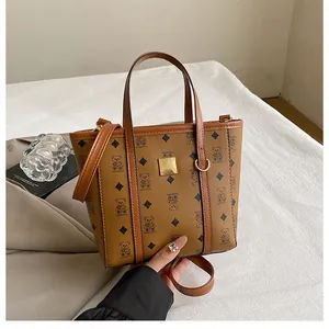 Detail view of brown faux leather bucket bag with bear monogram pattern and metal plaque