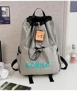 Detail of grey waterproof drawstring backpack with plush bear charm and Komilo logo