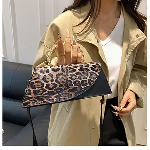 Detail of leopard print suede and black leather crossbody bag with gold woven handle