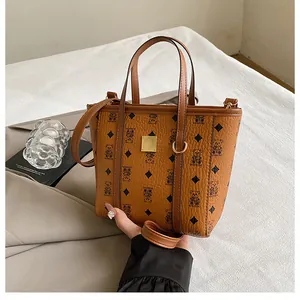 Detail of a brown bucket bag with bear print and gold metal plaque on a white fabric