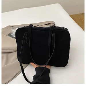 Detail of minimalist black matte handbag with slim straps and secure zipper closure