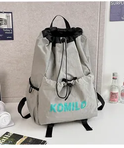 Macro detail of lightweight grey drawstring bag with KOMILO logo on nylon fabric