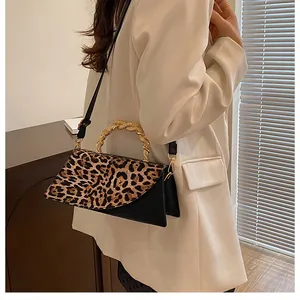 Detail of leopard print crossbody bag with unique gold textured metal handle on white blazer