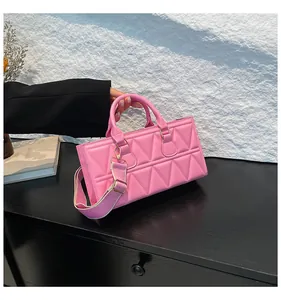 Detail of pink quilted handbag with adjustable striped wide shoulder strap and gold hardware