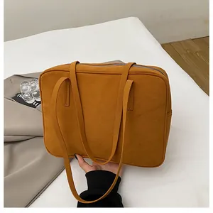 Detail of ochre suede tote bag showing soft matte texture and metal zipper closure