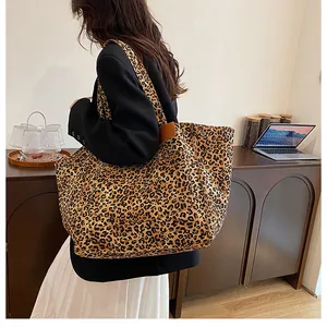 Detail showing high-capacity leopard print tote bag with brown leather accents