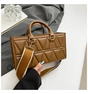 Detailed view of caramel brown leather handbag with geometric triangle quilting and wide strap