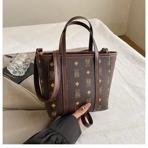 Close-up of brown monogram tote bag with teddy bear pattern and adjustable shoulder strap