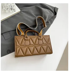 Detail of brown quilted leather handbag with chic triangular stitching and wide strap