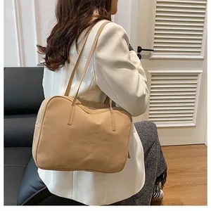 Close-up of khaki tote bag with matte leather texture worn by a model in a cozy setting