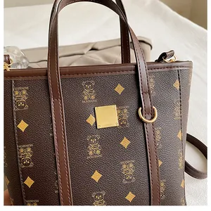 Detail of premium brown bucket bag with teddy bear pattern and golden hardware plate