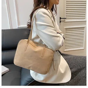 Detail of minimalist beige suede shoulder bag worn by a model in casual white suit