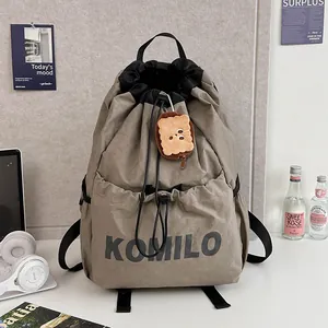 Lightweight khaki drawstring backpack with KOMILO logo and cute cookie charm on top