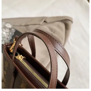Detailed close-up of dark brown leather handbag with gold zipper and fine stitching details