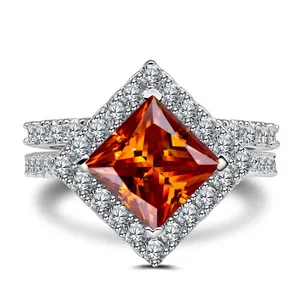 Detailed close-up of princess-cut orange sapphire ring with halo and pavé band