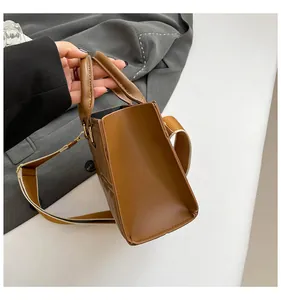 Detail view of the brown leather shoulder bag featuring a wide strap and sturdy side design