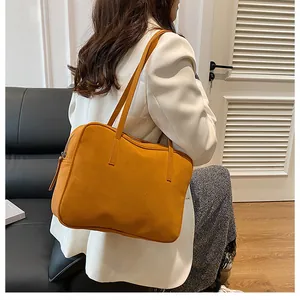 Detail of a ginger yellow matte tote bag on model shoulder with elegant white suit