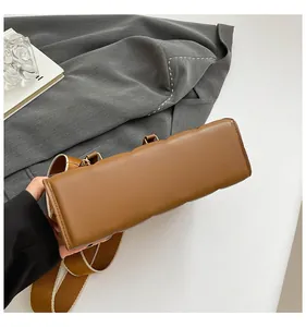 Detail view of brown leather bag showing thick bottom design and wide shoulder strap