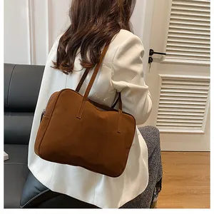 Close-up of caramel brown matte leather tote bag worn by model in a modern room
