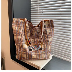 Close-up of orange plaid canvas tote bag with detailed dachshund embroidery on a book