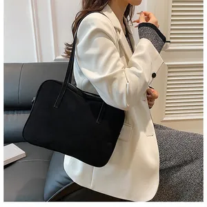 Detail of minimalist black tote bag paired with a white blazer for a professional look