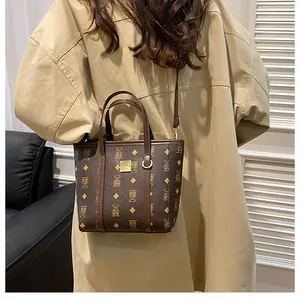 Detail of a dark brown mini tote bag featuring bear print and golden hardware on a model