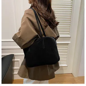 Detail of minimalist black matte crossbody bag featuring dual straps and metal zipper top