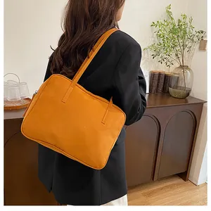 Detail of the orange frosted suede tote bag with dual straps worn over the shoulder