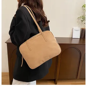 Close-up of matte camel brown leather shoulder bag with sleek dual strap and zipper details
