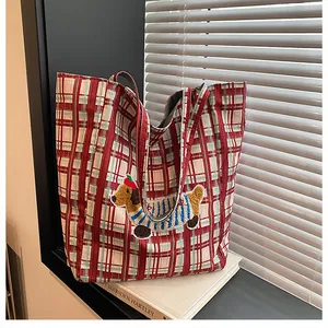 Detail of red checkered canvas tote with cute dachshund embroidery on a book by the window