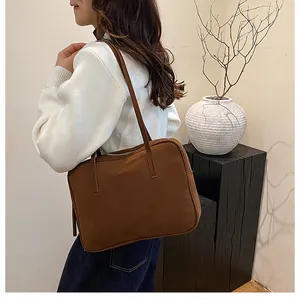 Detail view of deep brown frosted leather shoulder bag worn over a white sweater