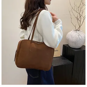Detail of dark brown matte tote bag showing the suede texture and slim shoulder straps