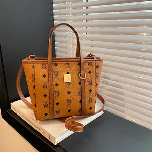 Brown vintage leather bucket bag with bear patterns and gold plaque on white books