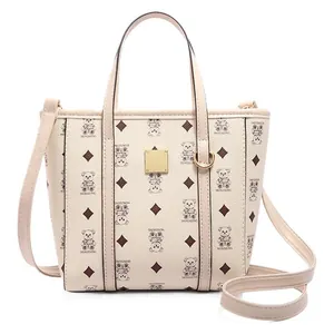 Creamy bucket bag with bear patterns and gold plaque, featuring hand and crossbody straps