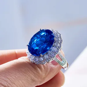 Dettaglio anello halo con zaffiro blu ovale da 15 carati su dito in argento S925