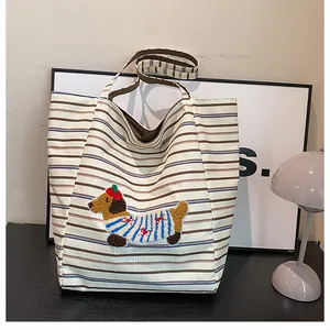 Close-up of beige corduroy tote bag with striped pattern and dog embroidery detail