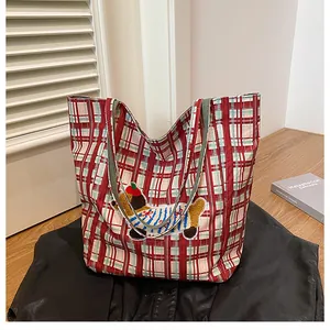 Close-up of red plaid canvas tote bag featuring cute cartoon dog embroidery and soft texture
