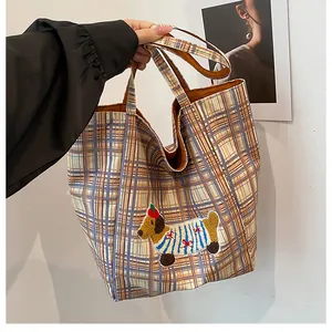Close-up of cute cartoon dog embroidery on a vintage plaid canvas tote bag