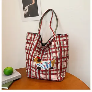 Close-up of red plaid canvas tote bag featuring an embroidered dachshund puppy patch