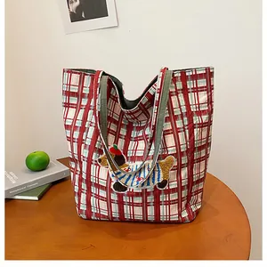 Detail of red checkered canvas tote bag with a cute dachshund embroidery and green handles