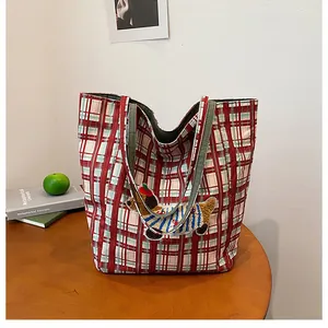 Detail of red plaid tote bag featuring a cute dachshund embroidery on a wooden table