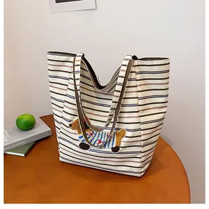Detail of corduroy tote bag with blue stripes and cute puppy embroidery on a table
