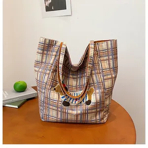 Detailed view of dog embroidery and yellow plaid pattern on spacious canvas tote bag