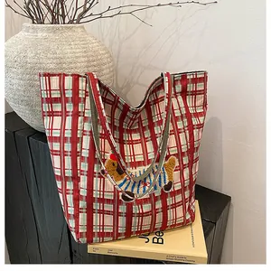 Detail of red checkered canvas tote with cute dog embroidery on a wooden stand