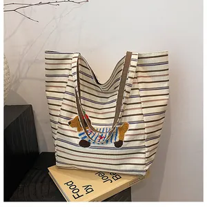 Detail of canvas tote bag featuring colorful stripes and cute embroidered dachshund dog