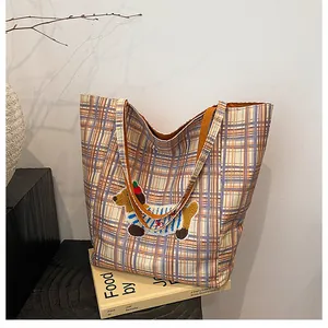 Detail of cute dachshund embroidery on a checkered orange and blue canvas tote bag