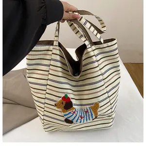 Detail of corduroy tote bag with colorful stripes and cute puppy embroidered patch