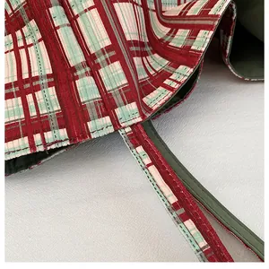 Detailed close-up of reinforced stitching on red and green plaid canvas tote bag