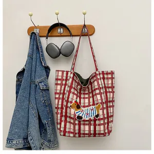 Close-up of cute cartoon puppy embroidery on a green and red checkered canvas tote bag
