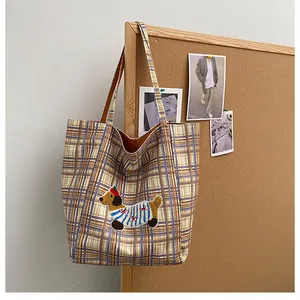 Close-up of checkered canvas tote bag featuring cute dachshund embroidery and brown handles